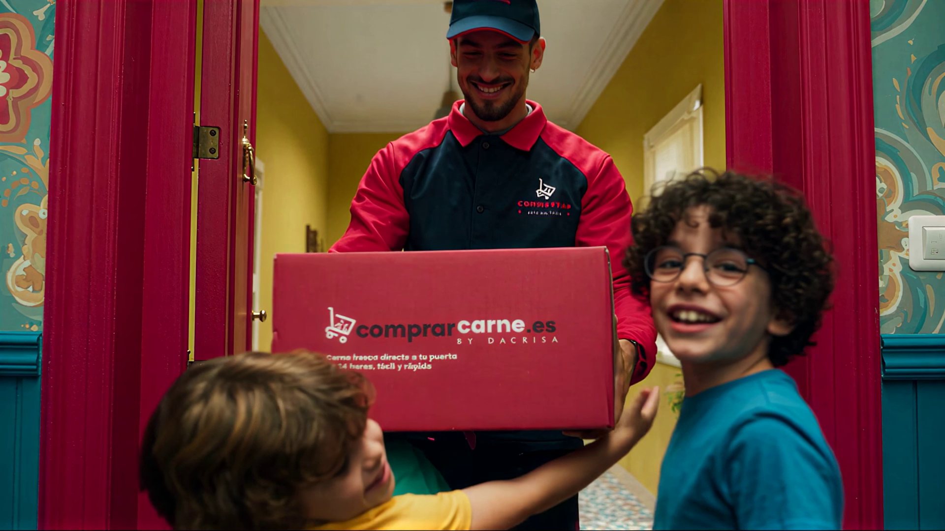 A courier hands the comprarcarne.es box to the boys at the door of a colourful home